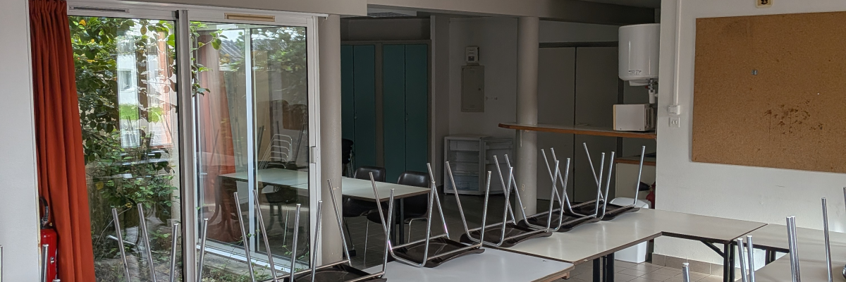 Salle de classe avec tables, chaises, tableau blanc et projecteur.