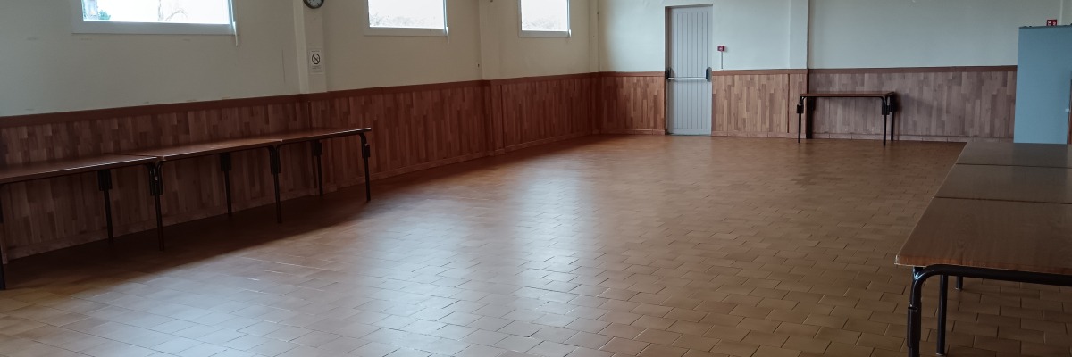Salle avec bancs en bois, tables, carrelage et fenêtres.
