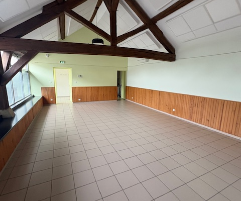 Pièce vide avec plancher carrelé, murs en bois, plafond blanc et poutres apparentes.