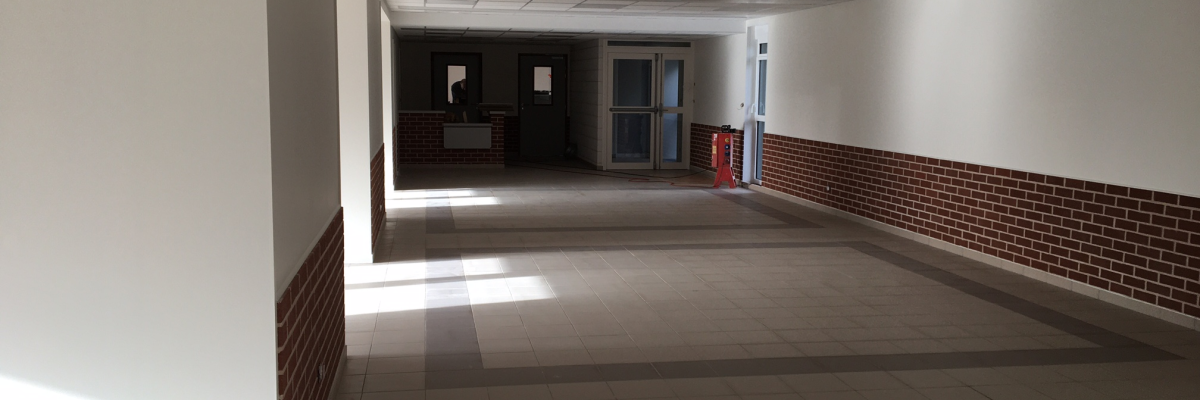 "Couloir avec portes, extincteur, sol carrelé et murs peints."