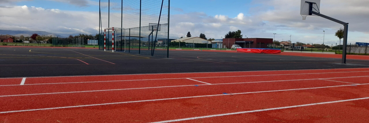 Terrain sportif avec pistes, paniers de basket et filets.