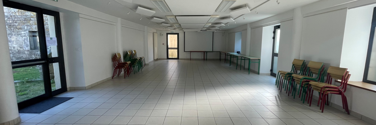 Salle spacieuse avec chaises, tables, lumières et portes.