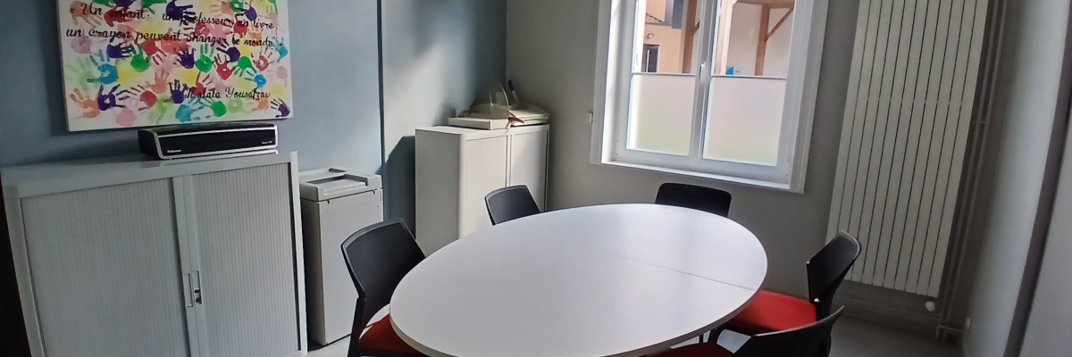 Salle avec table ronde, chaises, armoire, radiateur et fenêtre.