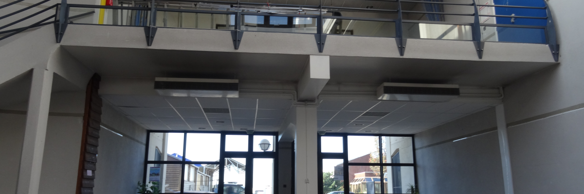 Salle avec balcon, rampes, table, plantes, fenêtres et lumière naturelle.