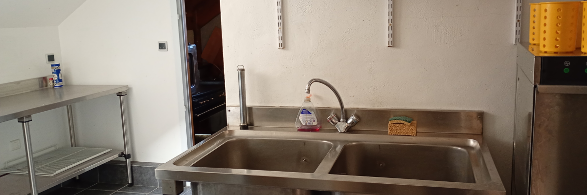 Cuisine avec évier, étagères, meubles métalliques et micro-ondes.