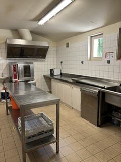 Cuisine avec plans de travail, four, évier, micro-ondes et étagères.