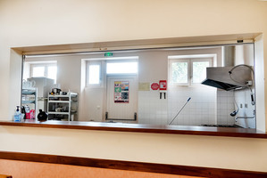 Cuisine avec plans de travail, étagères, évier, porte et cheminée.