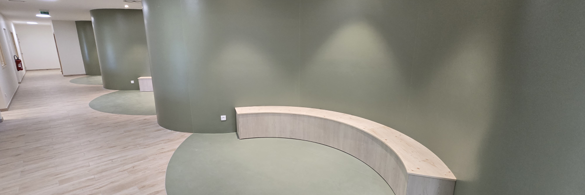 Espace intérieur moderne avec banc circulaire en bois et mur vert foncé.