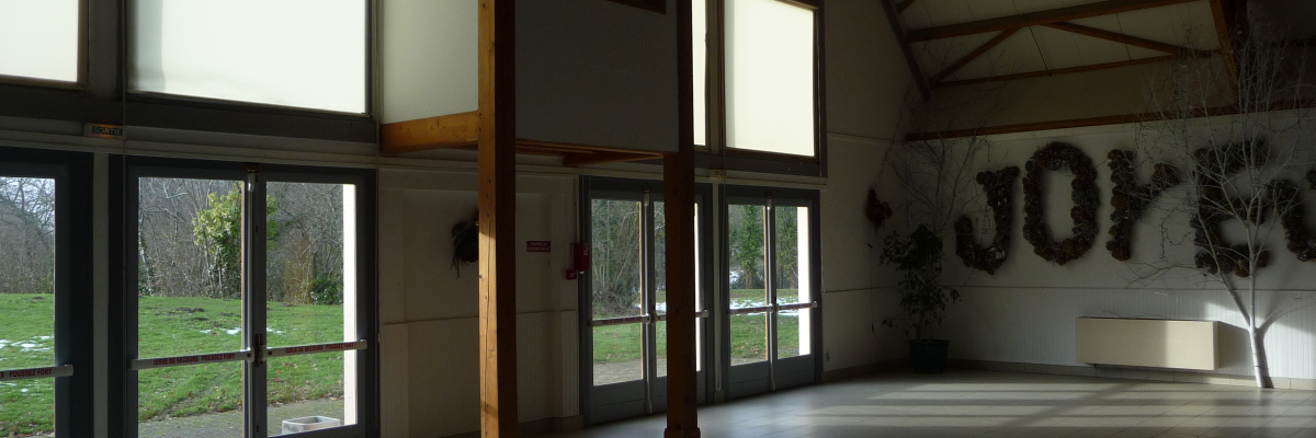 Salle avec grandes baies vitrées, portes, murs décors, toit pentu et mobilier minimaliste.