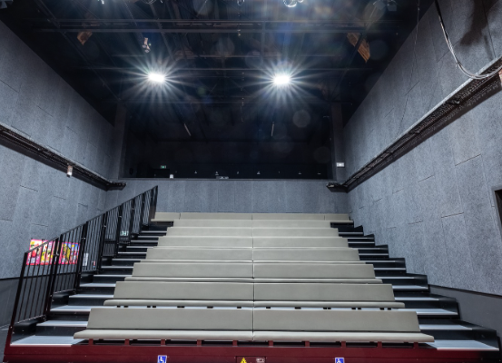 Salle avec gradins, tapis rouge et éclairages.