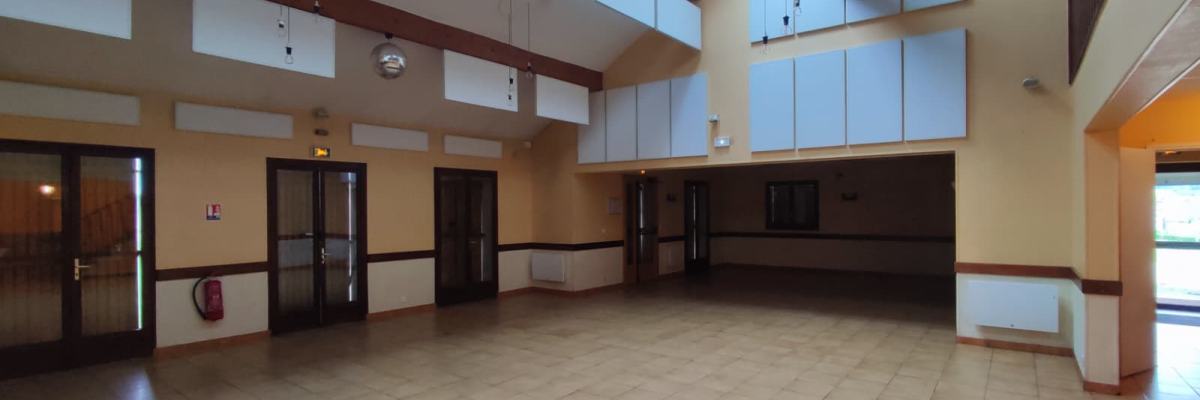 Salle spacieuse avec sols carrelés, plafonds hauts, rangements muraux, portes vitrées et naturels.