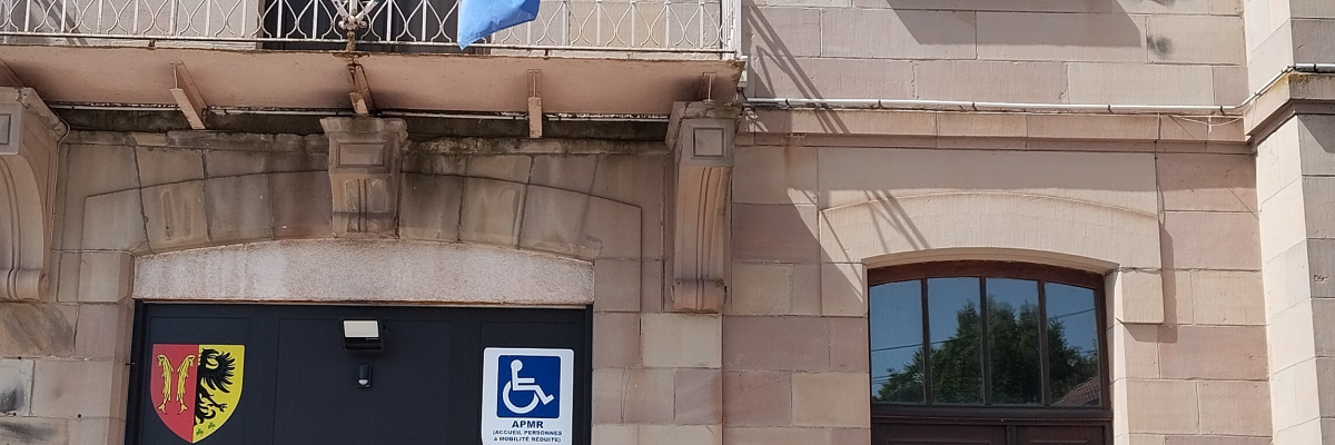 Bâtiment avec entrée, fenêtres, drapeaux, et panneaux de signalisation.