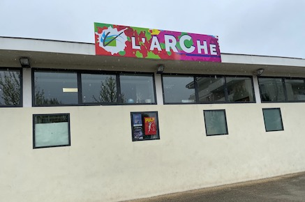 Bâtiment avec enseigne colorée "L'ARCHE", fenêtres et affiches.