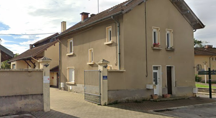 Maison mitoyenne, portail en métal, allée pavée, antenne TV, muret.