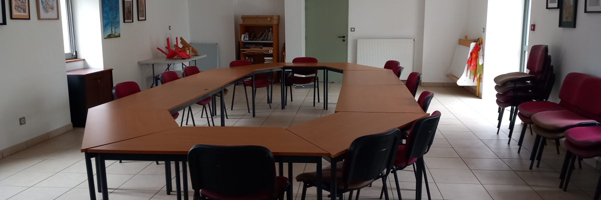Salle avec tables, chaises, radiateur, et tableaux sur les murs.