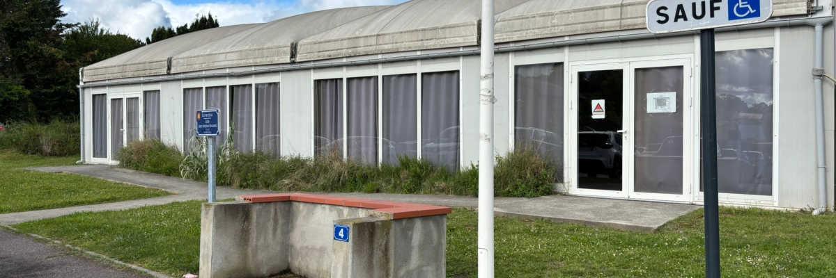 Bâtiment avec entrée, banc, panneau d'interdiction de stationner et panneau d'accessibilité.