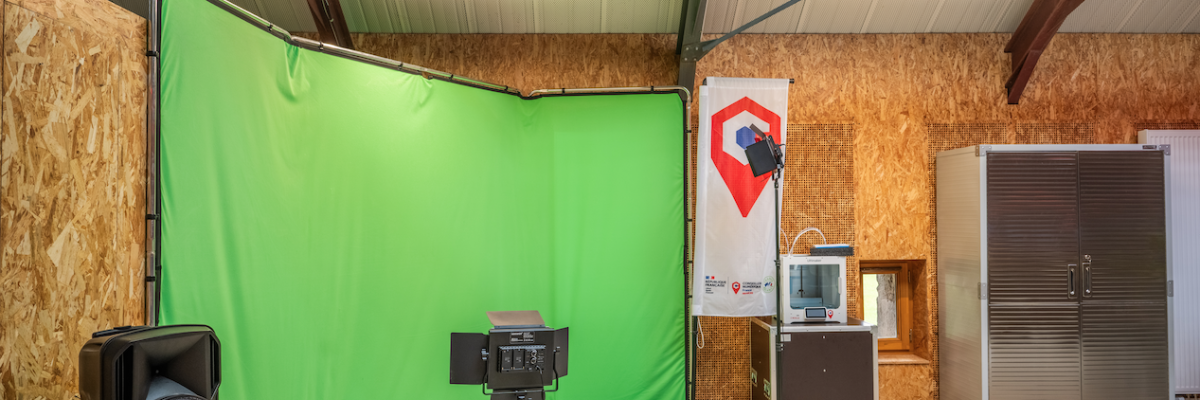 Studio vert avec écran, caméra sur trépied, table de mixage, enceintes, et porte métallique.