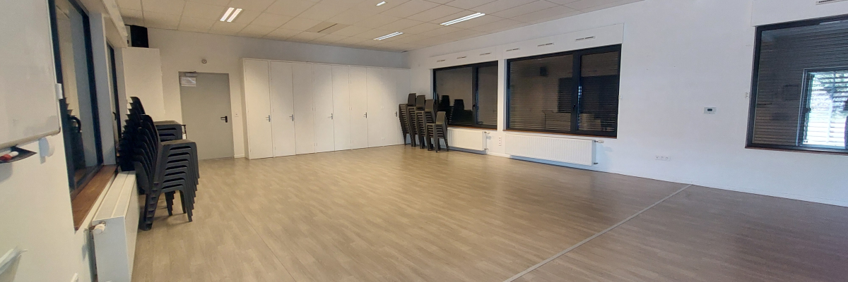 Salle vide avec chaises, portes, fenêtres et radiateurs.