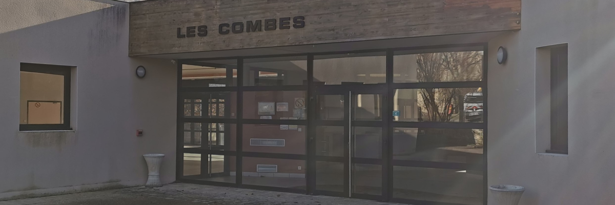 Entrée d'immeuble avec portes vitrées, enseigne et urinoirs extérieurs.