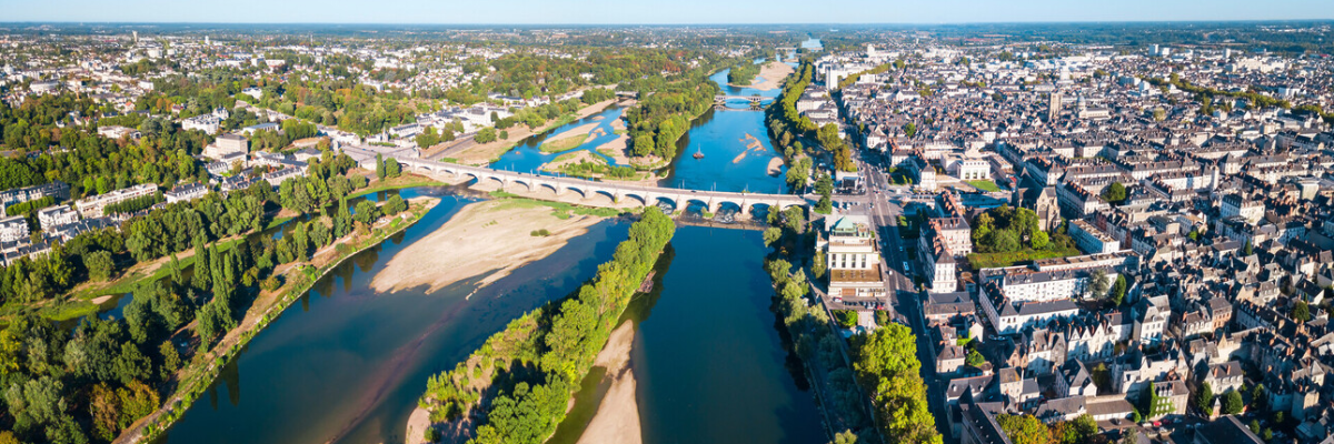 Ville traversée par une rivière avec ponts, bâtiments et verdure.