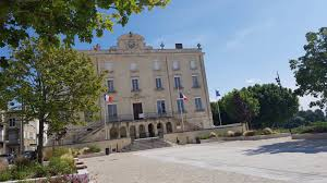 Grande bâtisse avec drapeaux, cour et arbres.