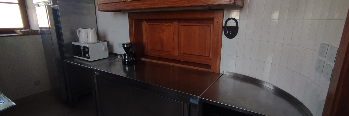 Cuisine avec comptoir, armoires en bois, réfrigérateur, bouilloire, grille-pain et meuble sous l'évier.