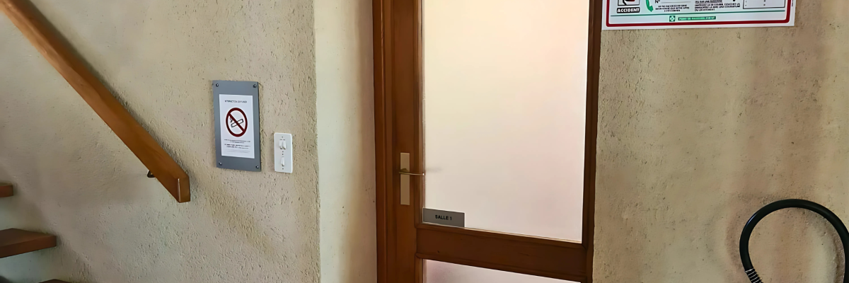 Un escalier, une porte, un extincteur, une alarme incendie et un panneau de sécurité.