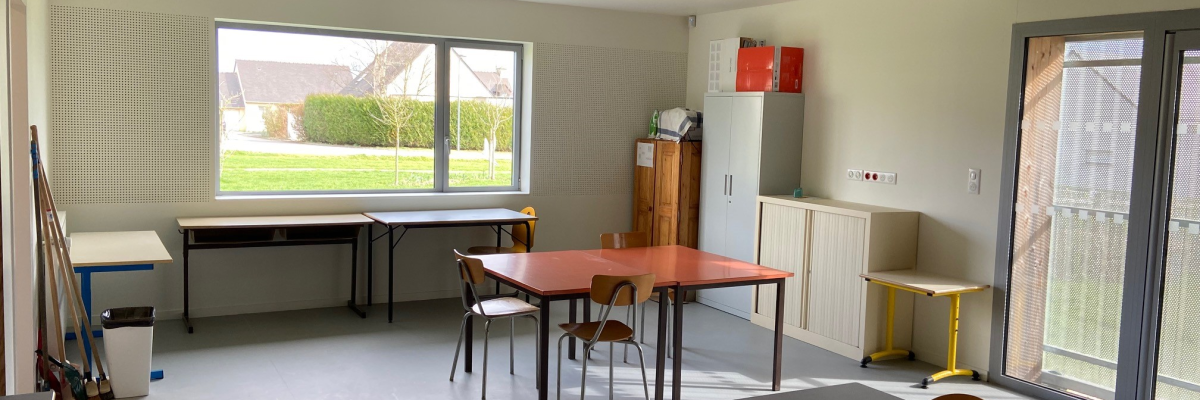 Salle avec tables, chaises, armoires, tableau blanc et échelles.