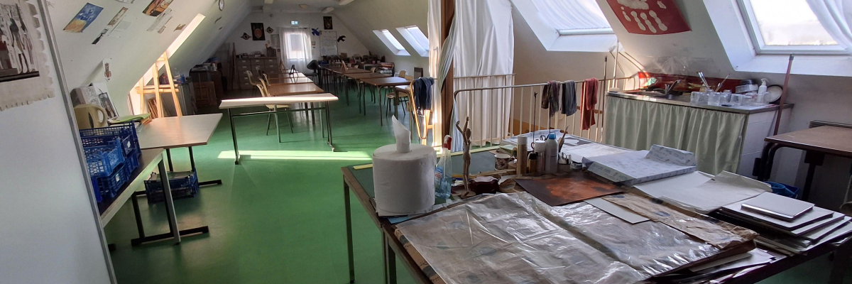 Atelier avec tables, outils, fenêtres et rangements.