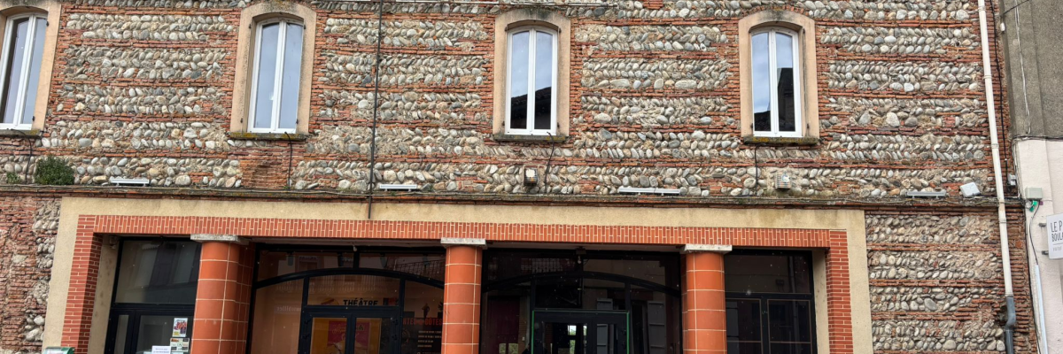 Bâtiment en brique avec trois fenêtres à arcades, entrée centrale, voiture stationnée devant.