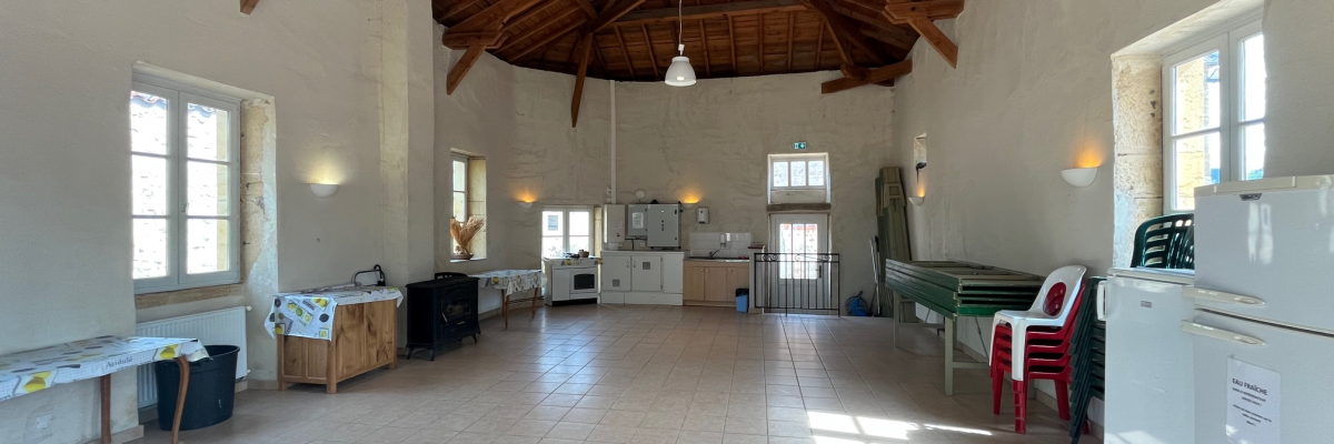 Pièce avec plafond en bois, tables, chaises, réfrigérateur, évier, et fenêtres.