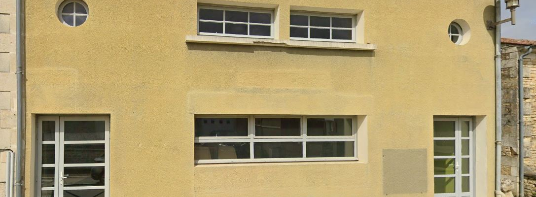 Bâtiment avec fenêtres, portes et barrières de parking.