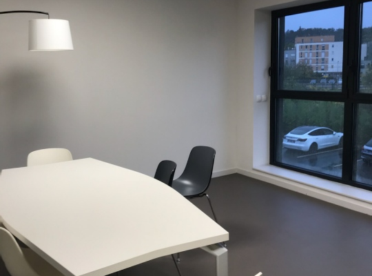 Salle de réunion avec table, chaises, lampe et fenêtre.