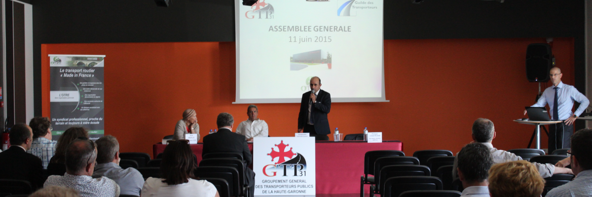 Assemblée générale avec écran, podium, projecteur, chaises et public.