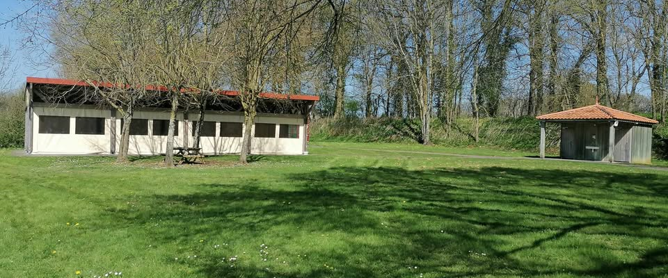 Deux bâtiments avec toits rouges, table de pique-nique, gazebo, pelouse verte, arbres.