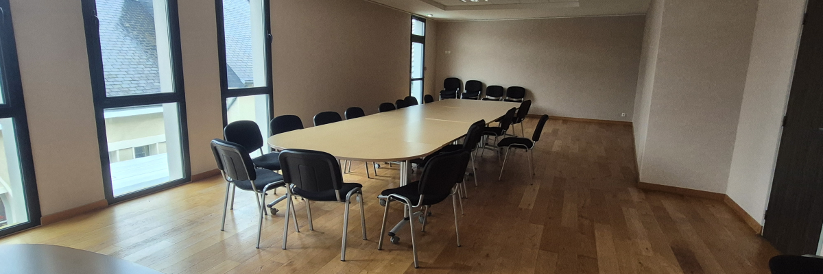 Salle de réunion avec table, chaises et fenêtres.