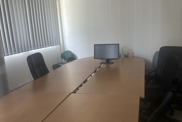 Salle de réunion avec table, chaises, ordinateur et climatiseur.