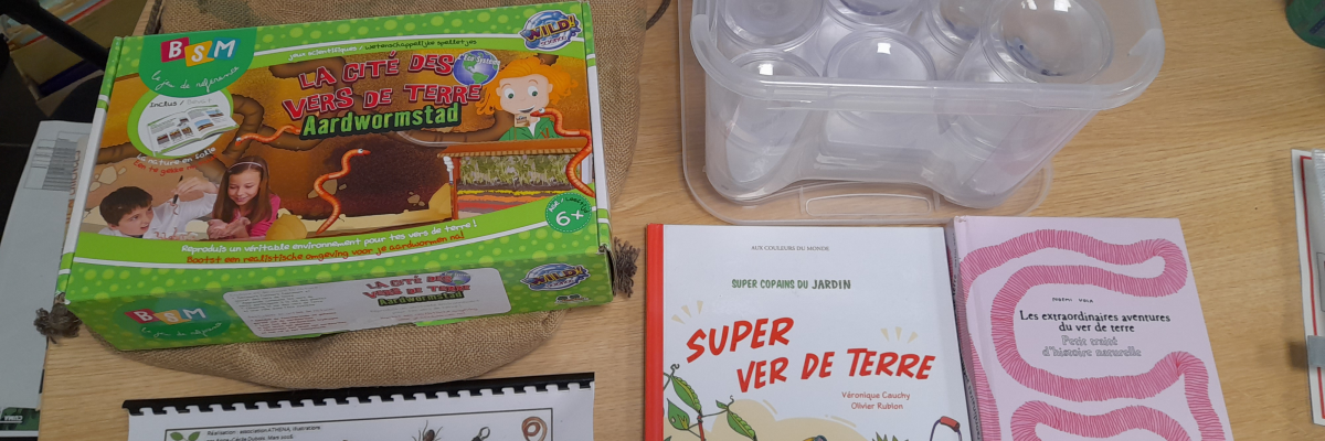 Sur une table, un sac en toile, une boîte de 24 pots transparents, un livre, un dépliant, une clé de détermination des petites bêtes du sol et un stylo.