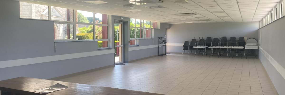 Salle avec tables, chaises, fenêtres et luminnaires.