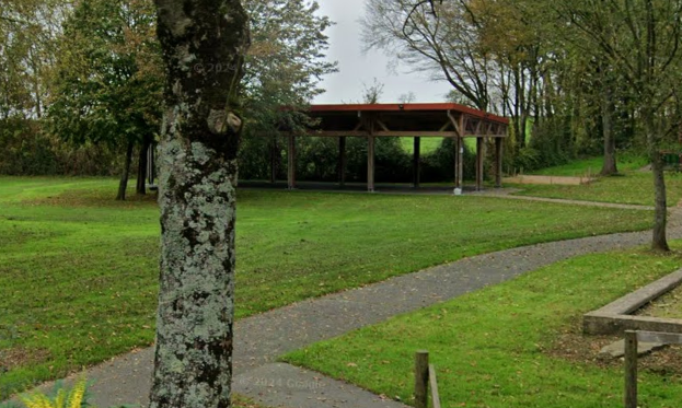 "Abri en bois sur pelouse, sentier, arbres."