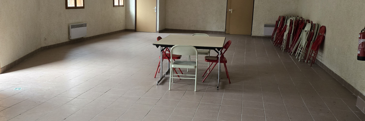Salle vide avec tables, chaises, extincteurs et rideaux.
