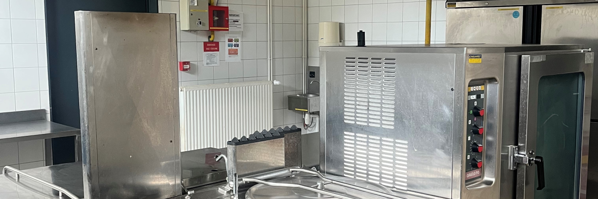 Cuisine avec hotte, plages de cuisson, fours et plans de travail.