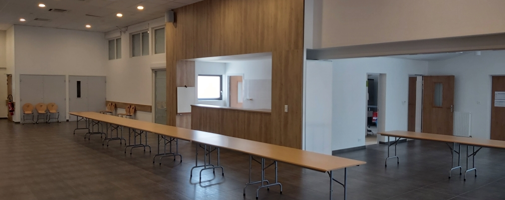 Salle avec tables, chaises, tableau blanc et projecteur.