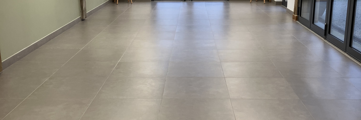 Pièce avec sol carrelé, portes vitrées, tabourets, et colonnes.