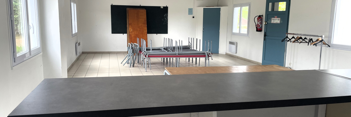 Salle avec table, chaises, tableau, porte-manteau et radiateur.