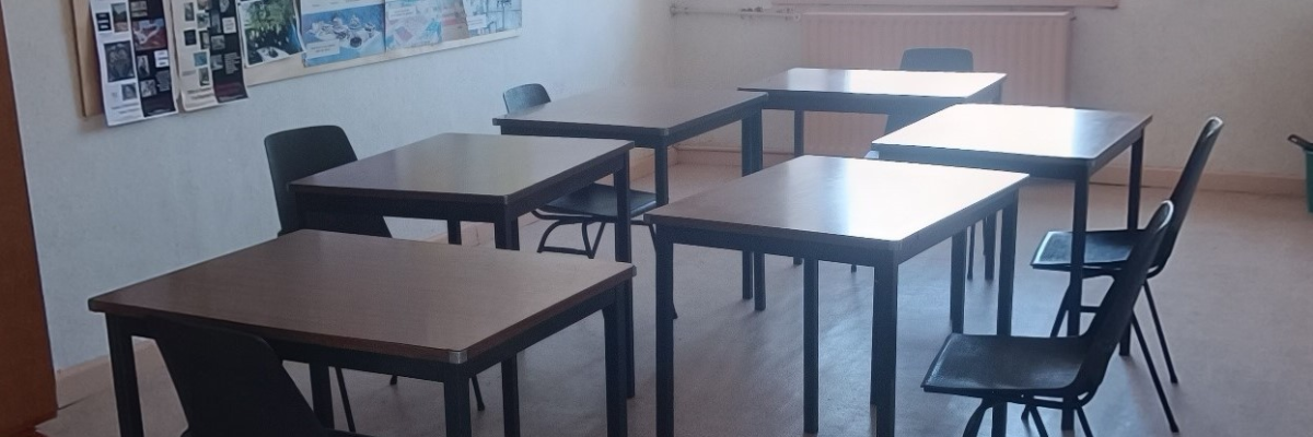 Salle avec tables, chaises, affiches.