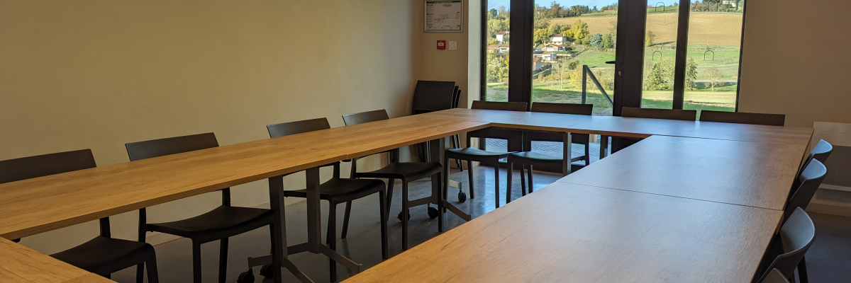 Salle de réunion avec table, chaises et fenêtres.