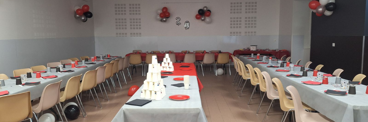 Salle avec tables, chaises, ballons, décorations.