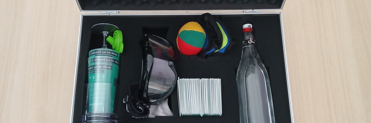 Valise ouverte contenant des lunettes de protection, une bouteille, un ballon, un spray et des documents.