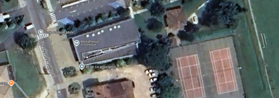 Vue aérienne d'un complexe sportif avec terrain de tennis, parking, et plusieurs bâtiments incluant un musée et une mairie.